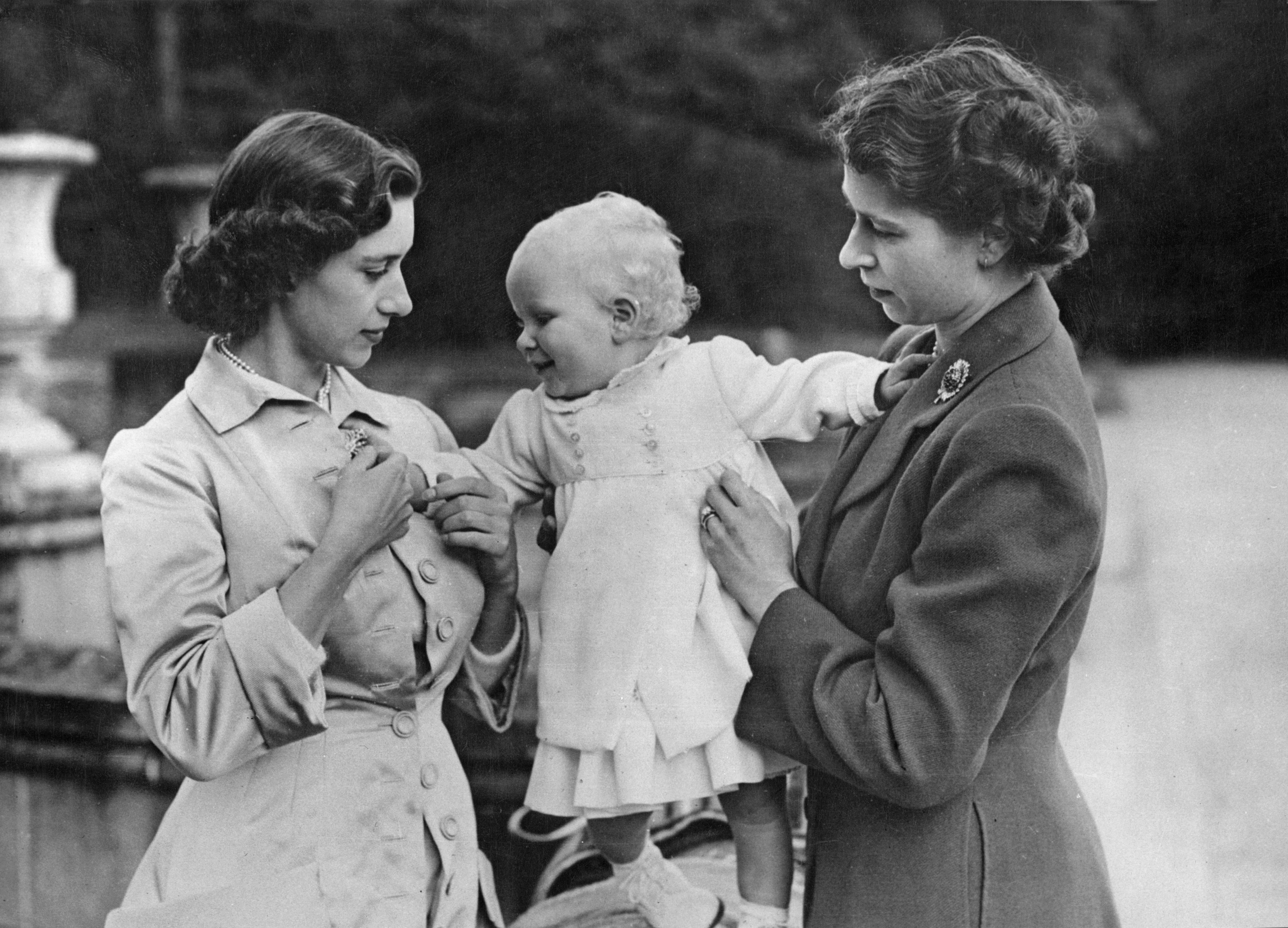 Princess Margaret and Queen Elizabeth holding a baby Princess Anne at Balmoral