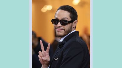 Pete Davidson giving the peace sign at The 2022 Met Gala Celebrating "In America: An Anthology of Fashion" at The Metropolitan Museum of Art on May 02, 2022 in New York City / on a blue and green background
