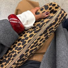 A woman with burgundy nails holding a stylish leopard print bag on the tube