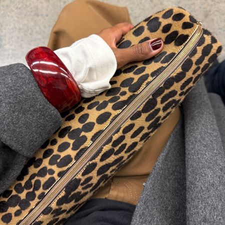 A woman with burgundy nails holding a stylish leopard print bag on the tube
