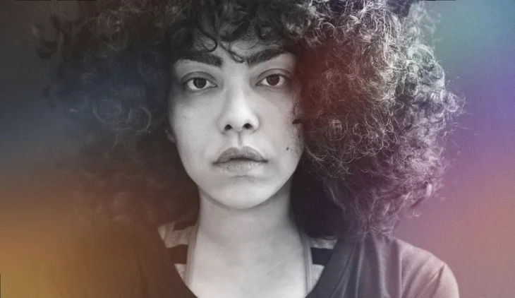 A woman with absolutely fabulous hair looks deep into the camera.