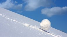 A growing snowball rolls down a hill.