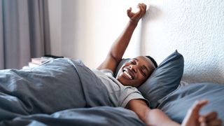 Man smiling and stretching in bed