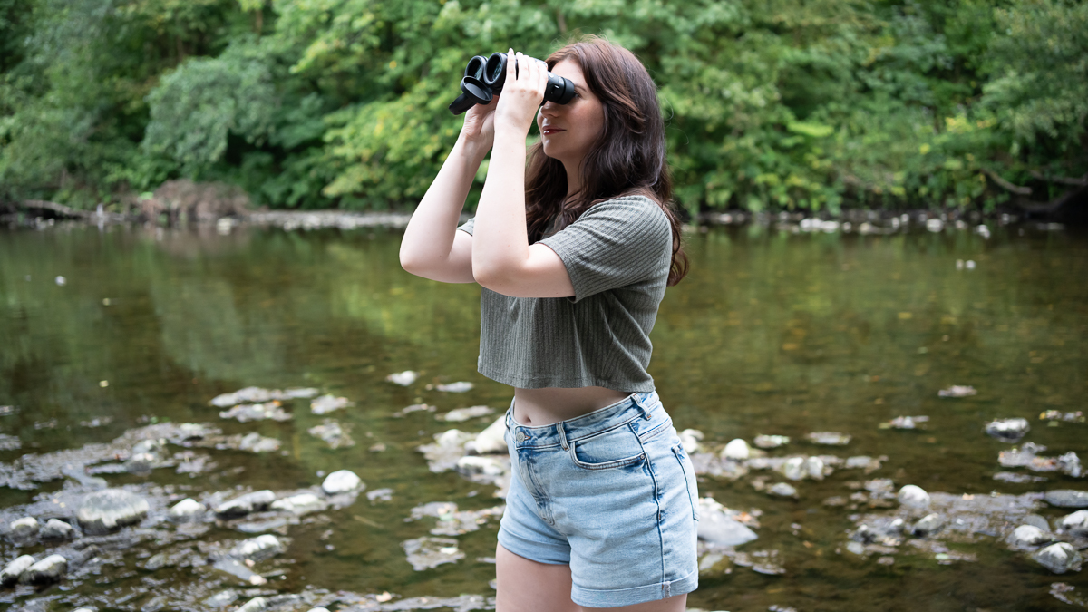 woman using the Celestron Regal ED 10x42 by a river