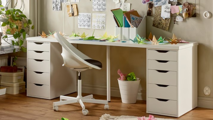 Two white IKEA ALEX drawer units flanking a wide desk surface in a decorated room