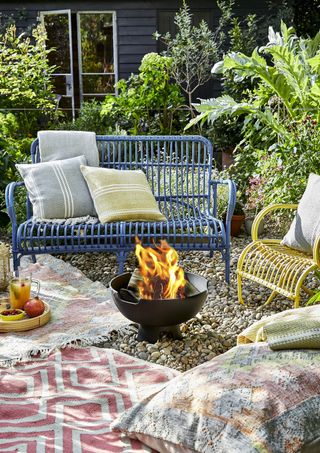 boho garden with a fire pit, several outdoor rugs and cushions