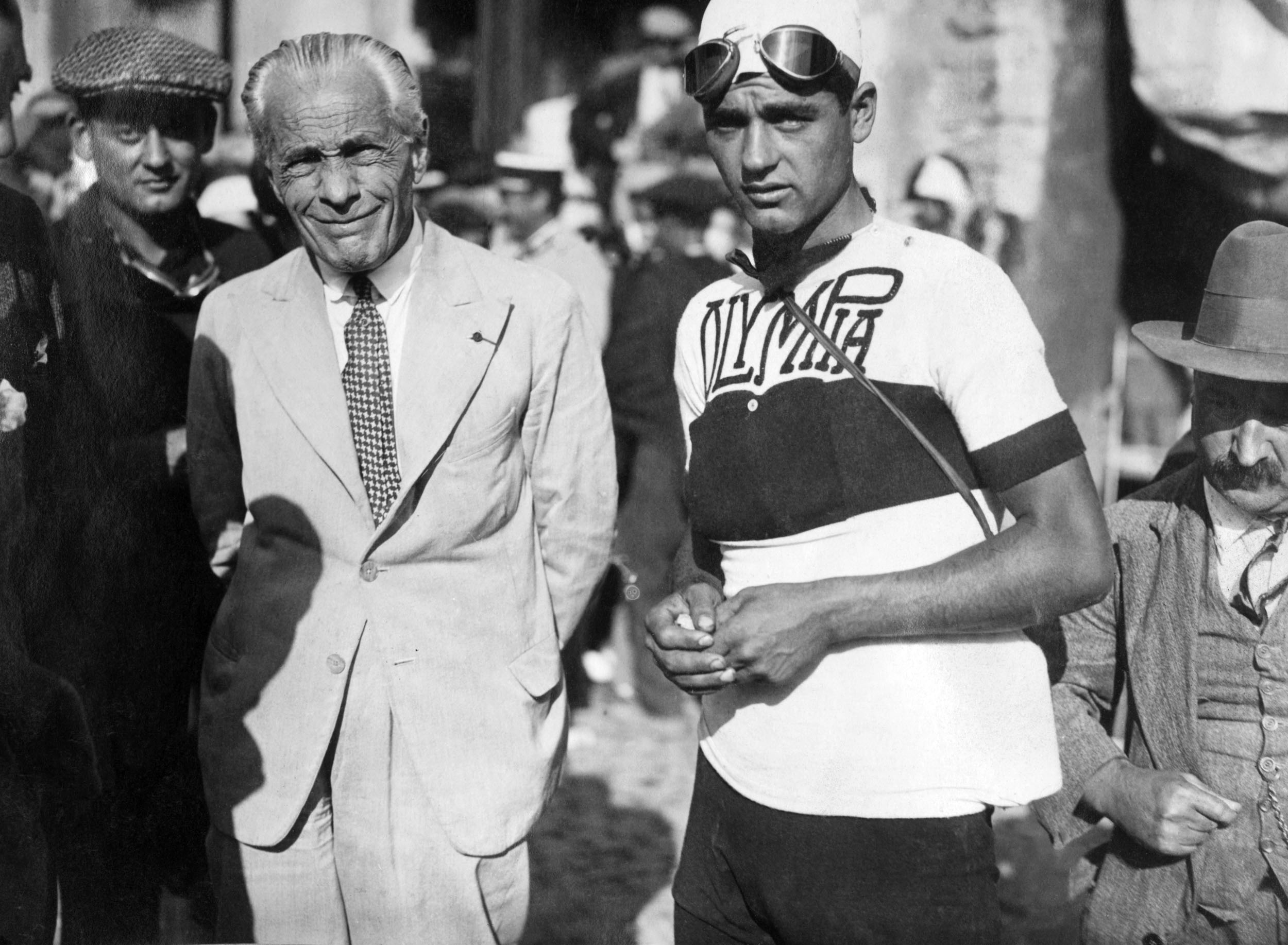 Henri Desgrange in a light-coloured suit, standing with a rider