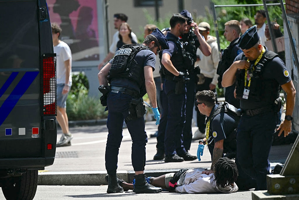 French Republican Security Corps (CRS - Compagnies Republicaines de Securite) officers detain an injured individual suspected to have stabbed a police officer near the finish line area of the 4th stage of the 112th edition of the Tour de France cycling race, 174.2 km between Amiens Metropole and Rouen, Northern France, on July 8, 2025. Police opened fire on an individual, wounding him in the leg before detaining him after he attacked and injured a police officer with a knife, near the finish line area in Rouen before the arrival of the 4th stage of the Tour de France cycling race. (Photo by Loic VENANCE / AFP) (Photo by LOIC VENANCE/AFP via Getty Images)