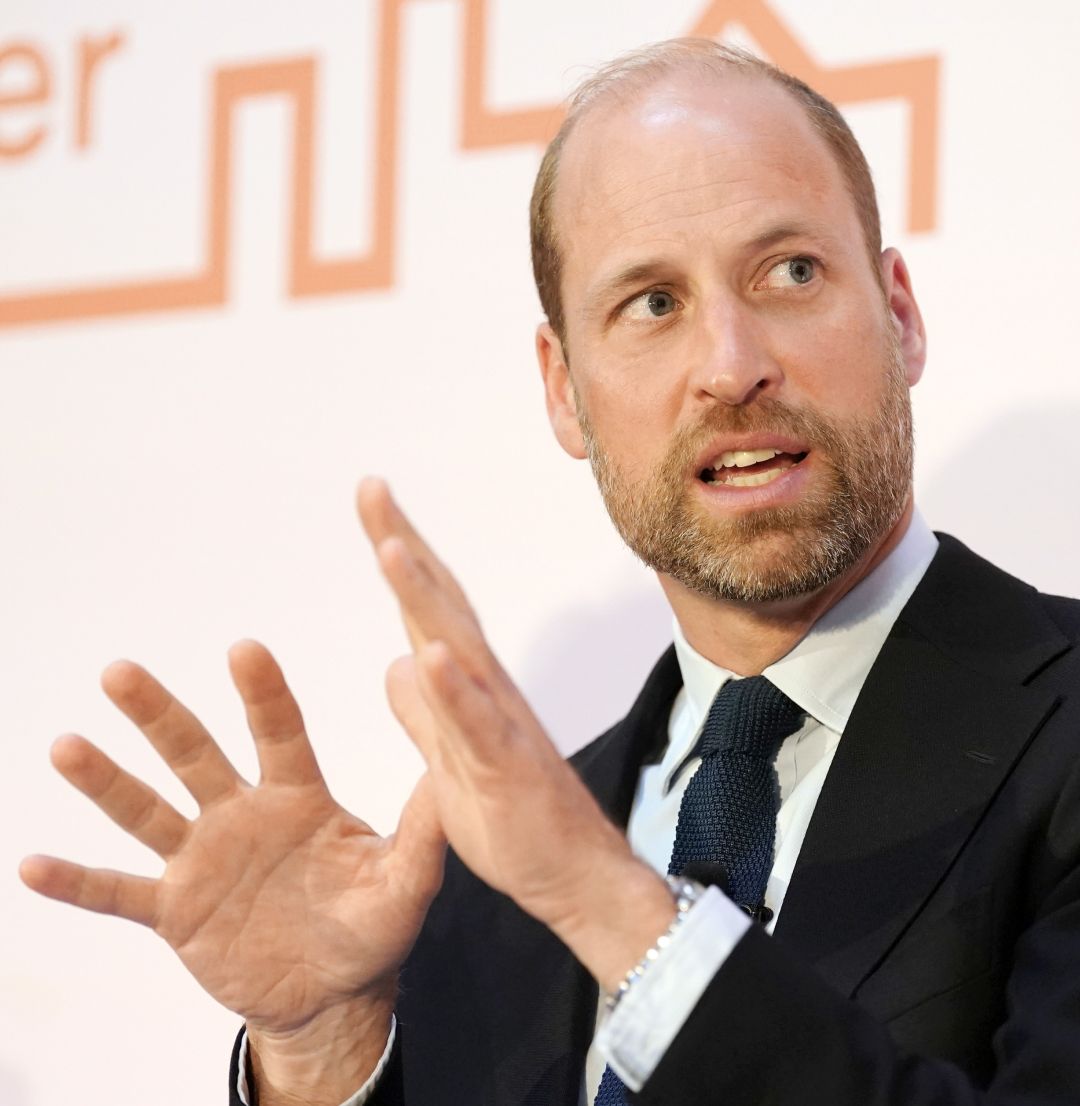 Prince William wearing a black suit and talking while gesturing with both hands