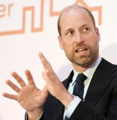 Prince William wearing a black suit and talking while gesturing with both hands