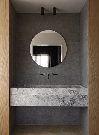 A minimalist bathroom vanity with a round mirror