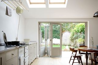 white and cream scheme kitchen with contemporary yet traditional feel in kitchen extension with bi-fold doors looking onto garden by devol