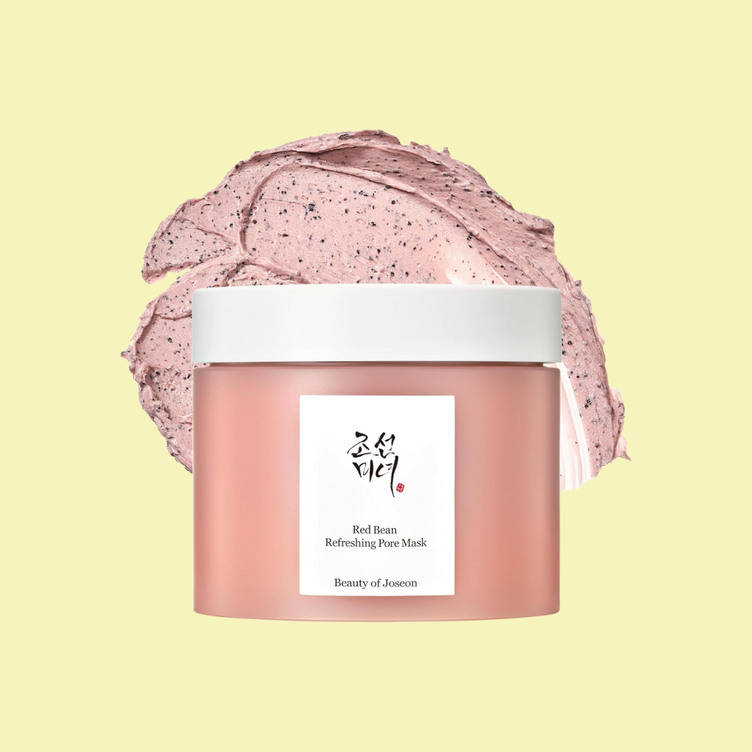 Beauty of Joseon Red Bean Refreshing Pore Mask in a pink and white tub sits against a pale yellow background and a black-dotted pink swathe of lotion.