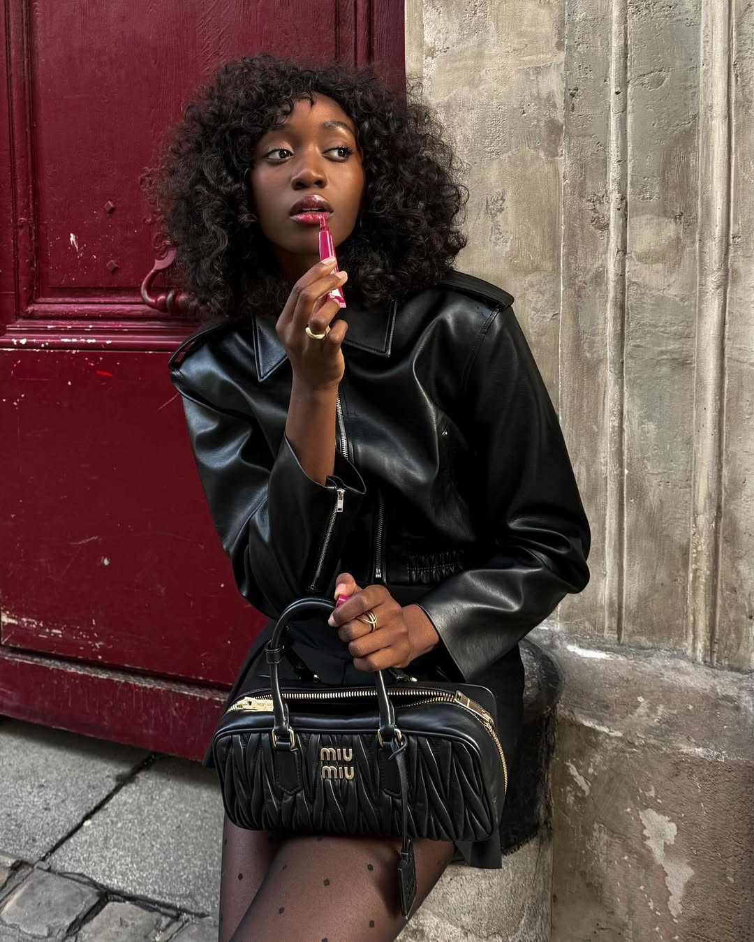 Emmanuelle Koffi wearing a black leather jacket with a curly bob