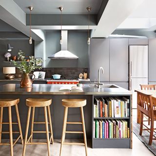 grey kitchen with worktops bookshelves and bar stools