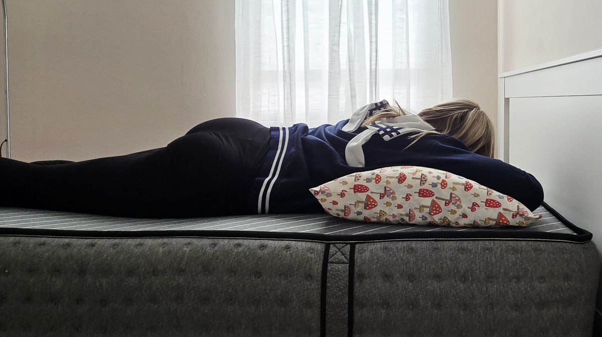 Mattress tester stomach sleeping on the Siena Premier Hybrid Mattress in her bedroom