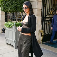 Kendall Jenner wears a black coat, silk top and silk skirt
