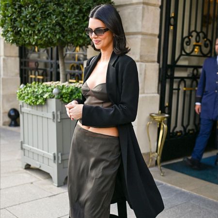 Kendall Jenner wears a black coat, silk top and silk skirt