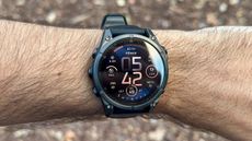 The default watch face on the Garmin Fenix 8 on the author's wrist. It shows a variety of small widgets like VO2 Max, acute load, time/date, steps, intensity minutes, and recovery time.