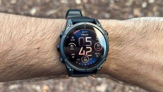 The default watch face on the Garmin Fenix 8 on the author's wrist. It shows a variety of small widgets like VO2 Max, acute load, time/date, steps, intensity minutes, and recovery time.