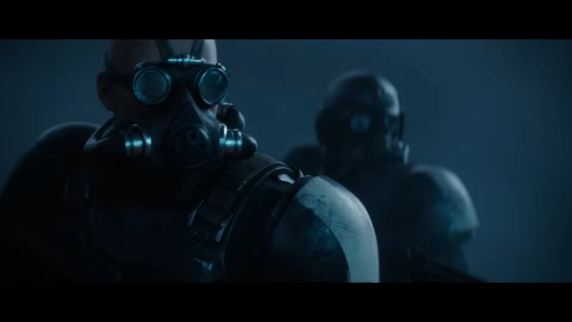 Two figures in dark, futuristic armor and gas masks stand in a dim, foggy environment. The scene conveys a tense, mysterious atmosphere.