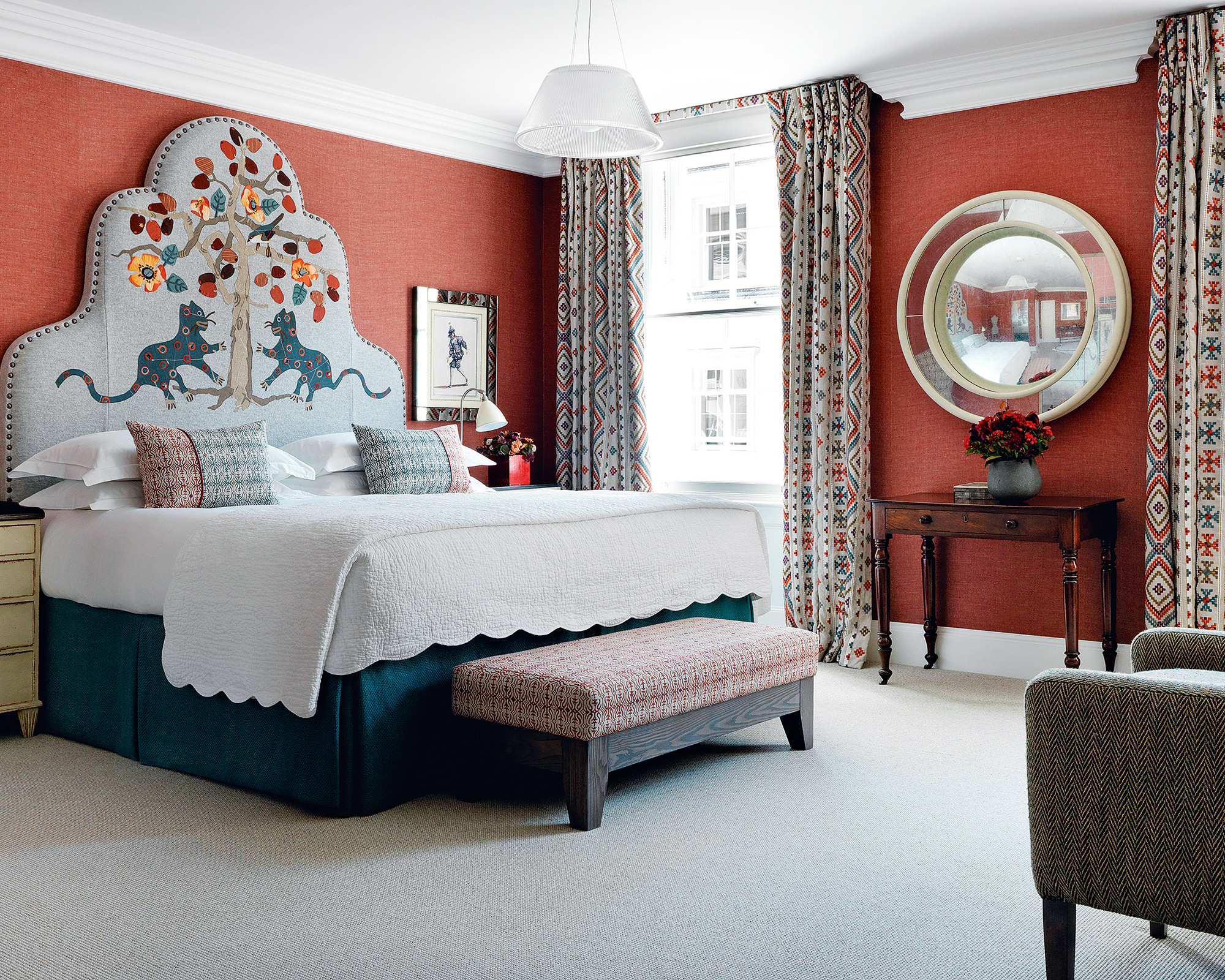 A grey bed featuring an impressive headboard adorned with cats pawing at a colourful tree