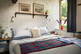 bedroom with whitewashed walls traditional bedlinen and pictures