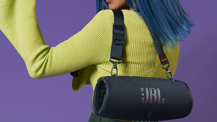 A JBL Bluetooth speaker slung over a girl's shoulder by a strap