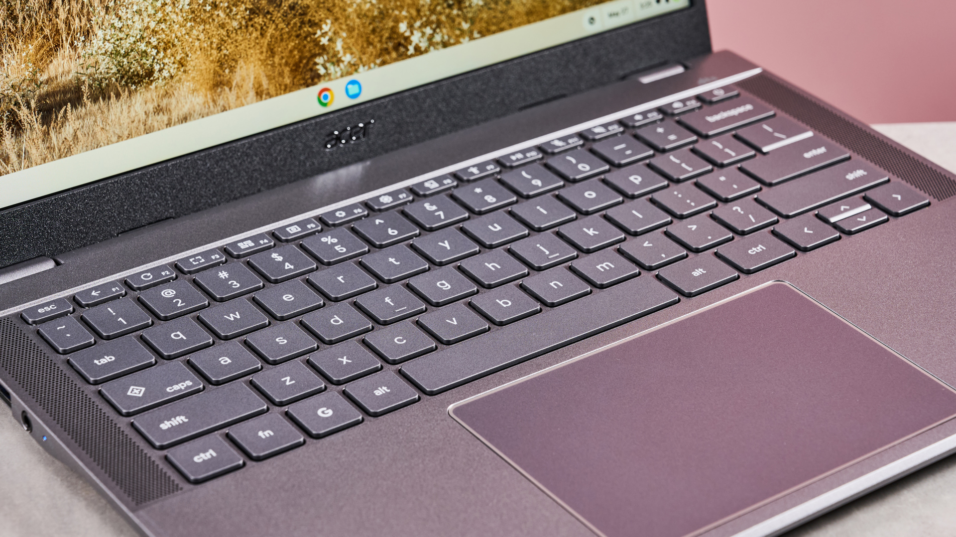 Close-up of keyboard and touchpad on Acer Chromebook Plus 516, open on desk with pink background