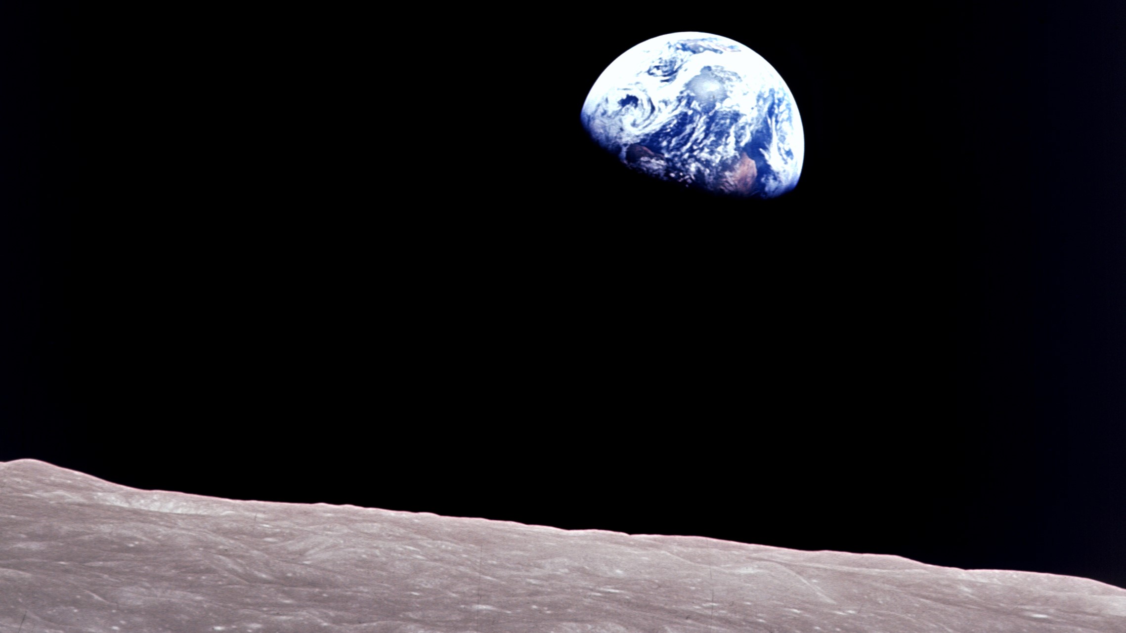 photo of earth in the distance with the moon's gray dirt in the foreground