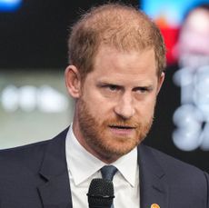 Prince Harry wearing a blue suit speaking into a microphone