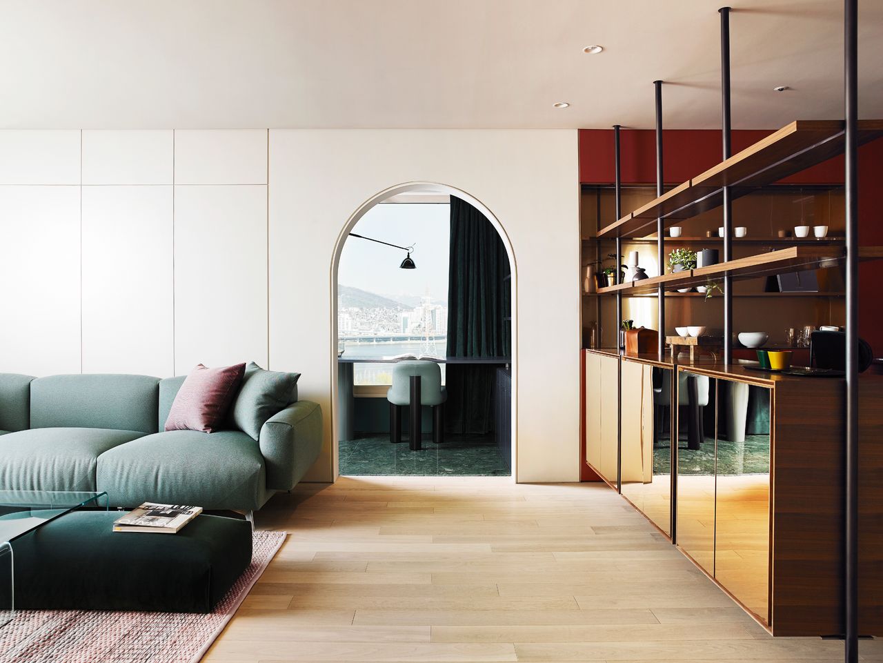 Living room with sofa and coffee table, shelving, and an archway into the next room