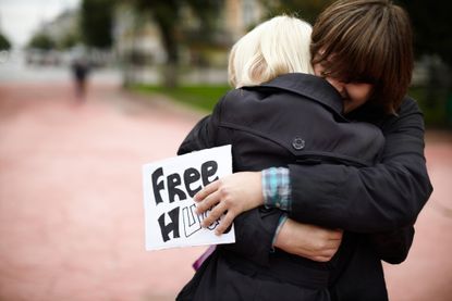 Samara, Russia - September 25, 2011: A young man hugs a blonde woman on the street, holding a sign offering "free hugs" to anyone on a gloomy and rainy autumn day.