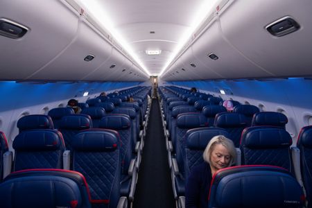 Passengers sitting in a mostly empty Delta airplane.