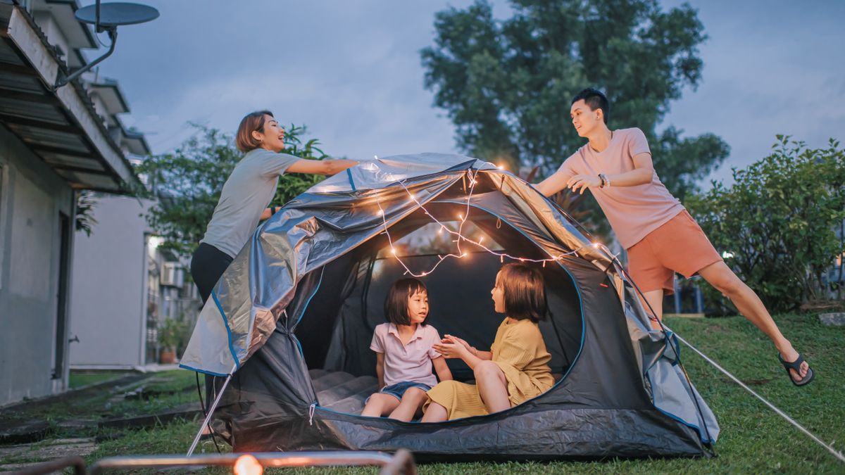 family putting on string light decorating camping at backyard of their house staycation weekend