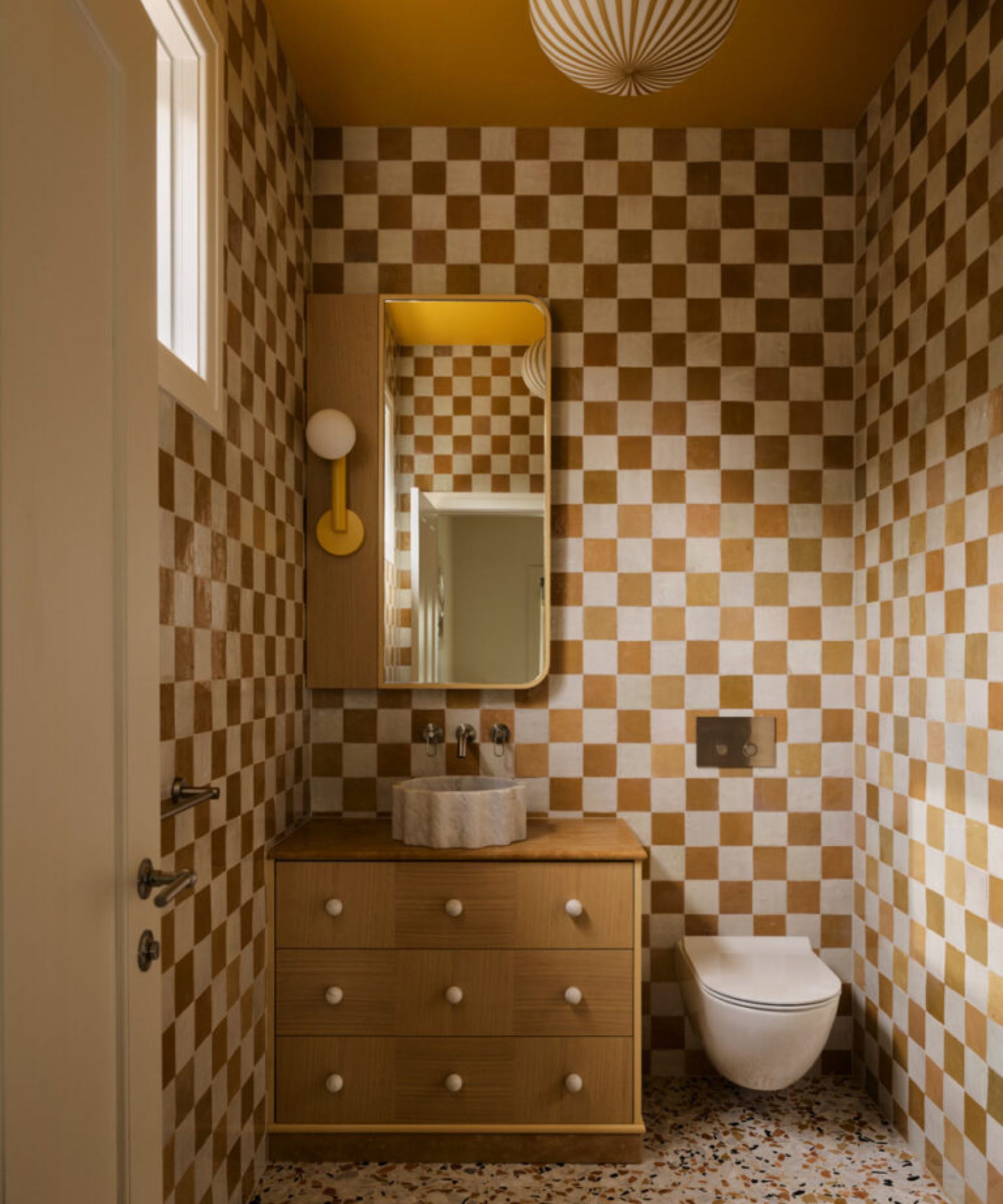 a bathroom with checker-printed walls in white and tan