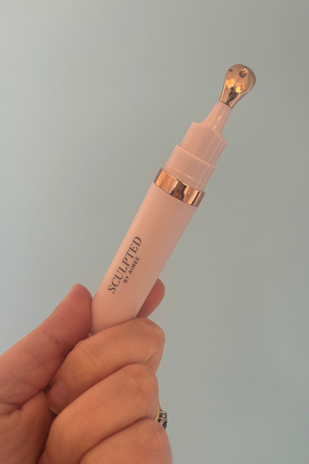 a hand holding a tube of sculpted by aimee eye cream