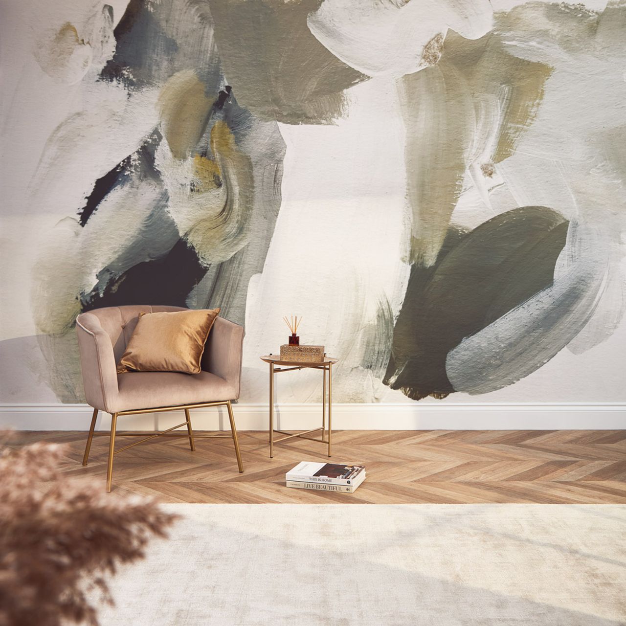 A living area with wallpaper with a paint stroke design, herringbone flooring and a pink velvet chair