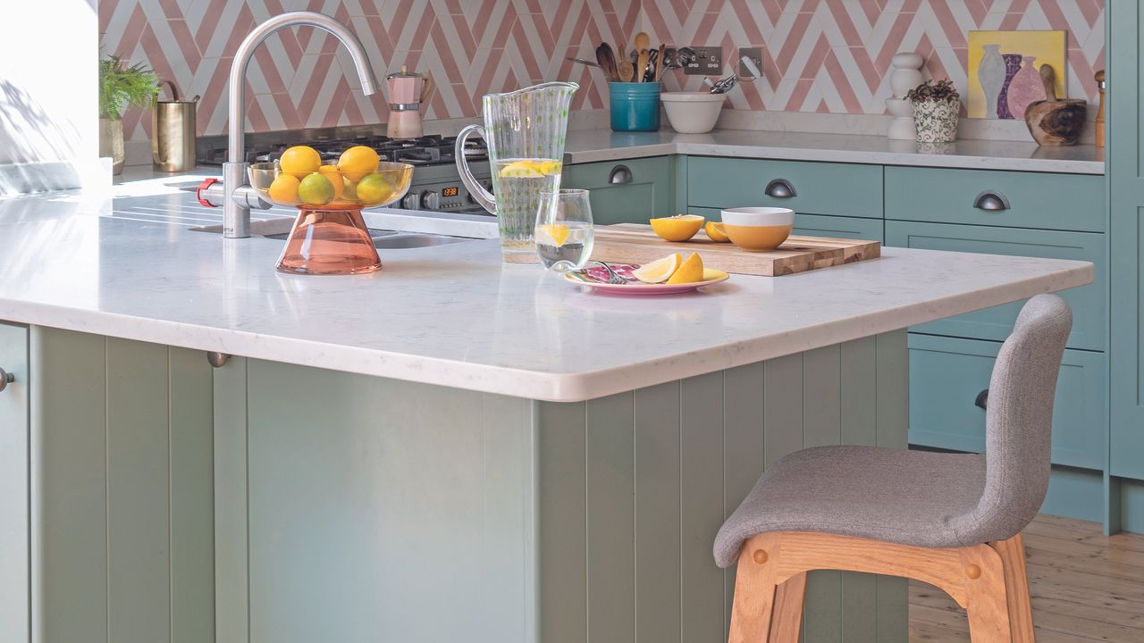 Green kitchen with white worktops and small island