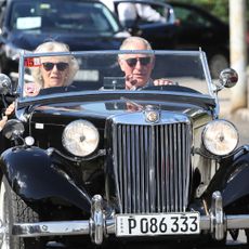 King Charles and Queen Camilla driving in a convertible