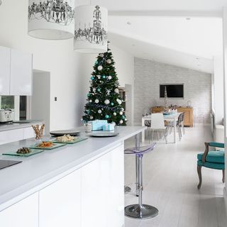 Christmas tree with blue white and silver decorations in white dining area