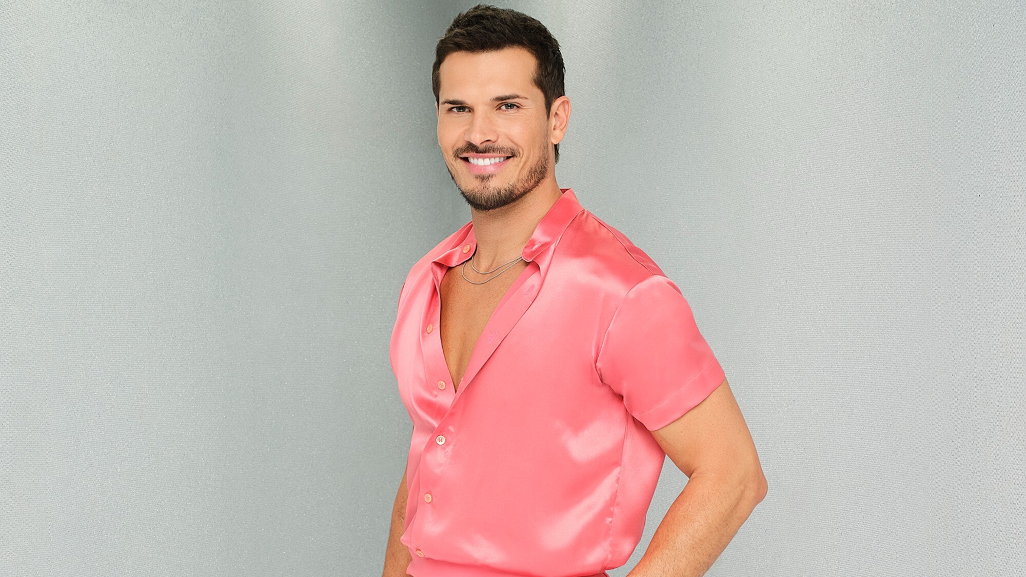 Dancing with the Stars pro dancer Gleb Savchenko smiling while wearing a pink satin shirt.