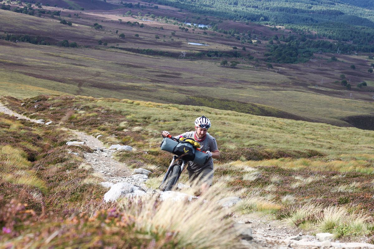 pushing a fully loaded bike up a mountain trail