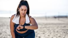 Woman on beach looking at fitness tracker