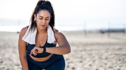 Woman on beach looking at fitness tracker