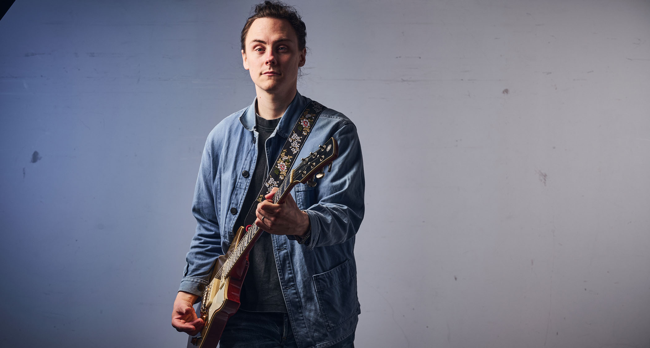 Chris Buck wears a denim jacket and plays his Yamaha goldtop Revstar.