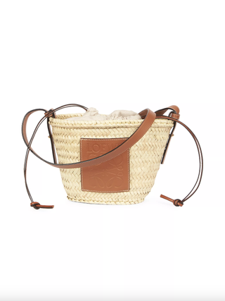 a straw bag by Loewe in front of a plain backdrop