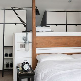 loft bedroom with night lamp on wall and alarm watch near wooden bed