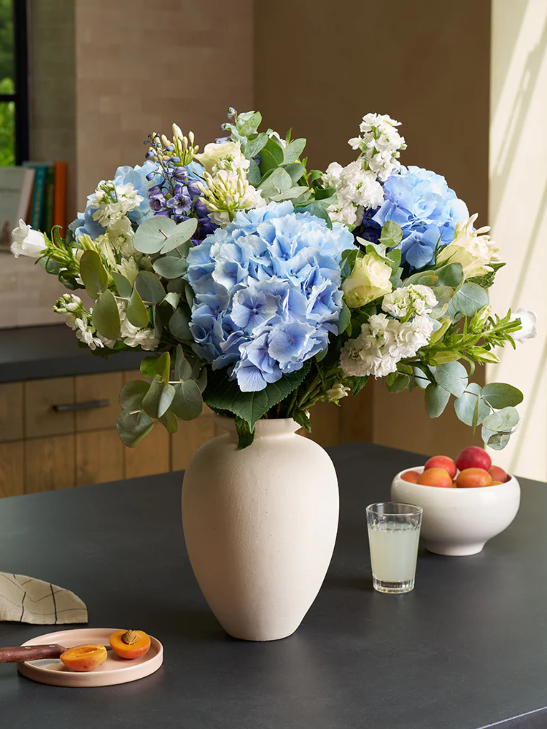 A vase with blue hydrangeas on a kitchen island