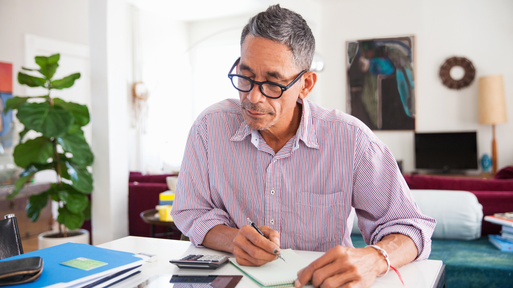 Mature man wearing eyeglasses working on personal finances at home